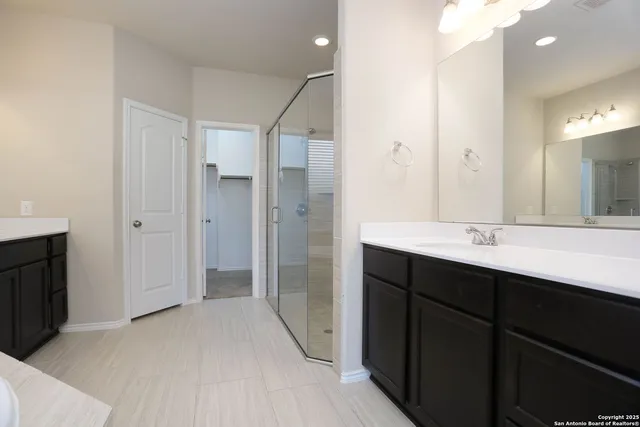a bathroom with a double vanity sink a large mirror and shower