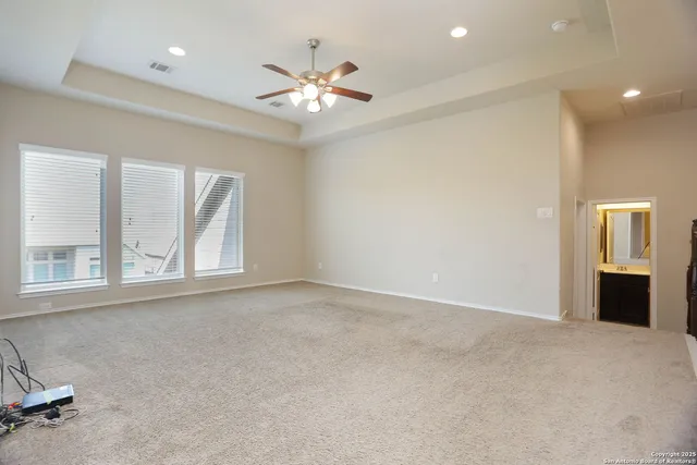 an empty room with chandelier fan and windows