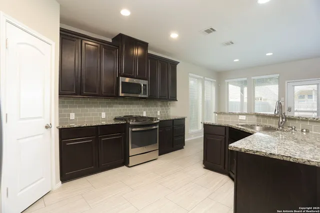 a kitchen with kitchen island granite countertop stainless steel appliances stove microwave sink and cabinets