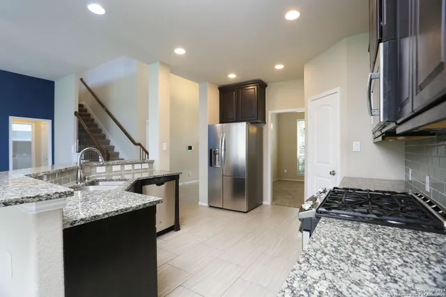 a kitchen with stainless steel appliances granite countertop a sink stove and refrigerator