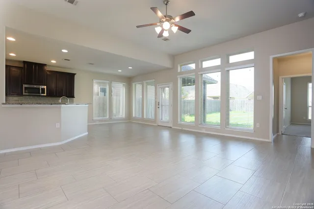 a view of an empty room with a window and a kitchen