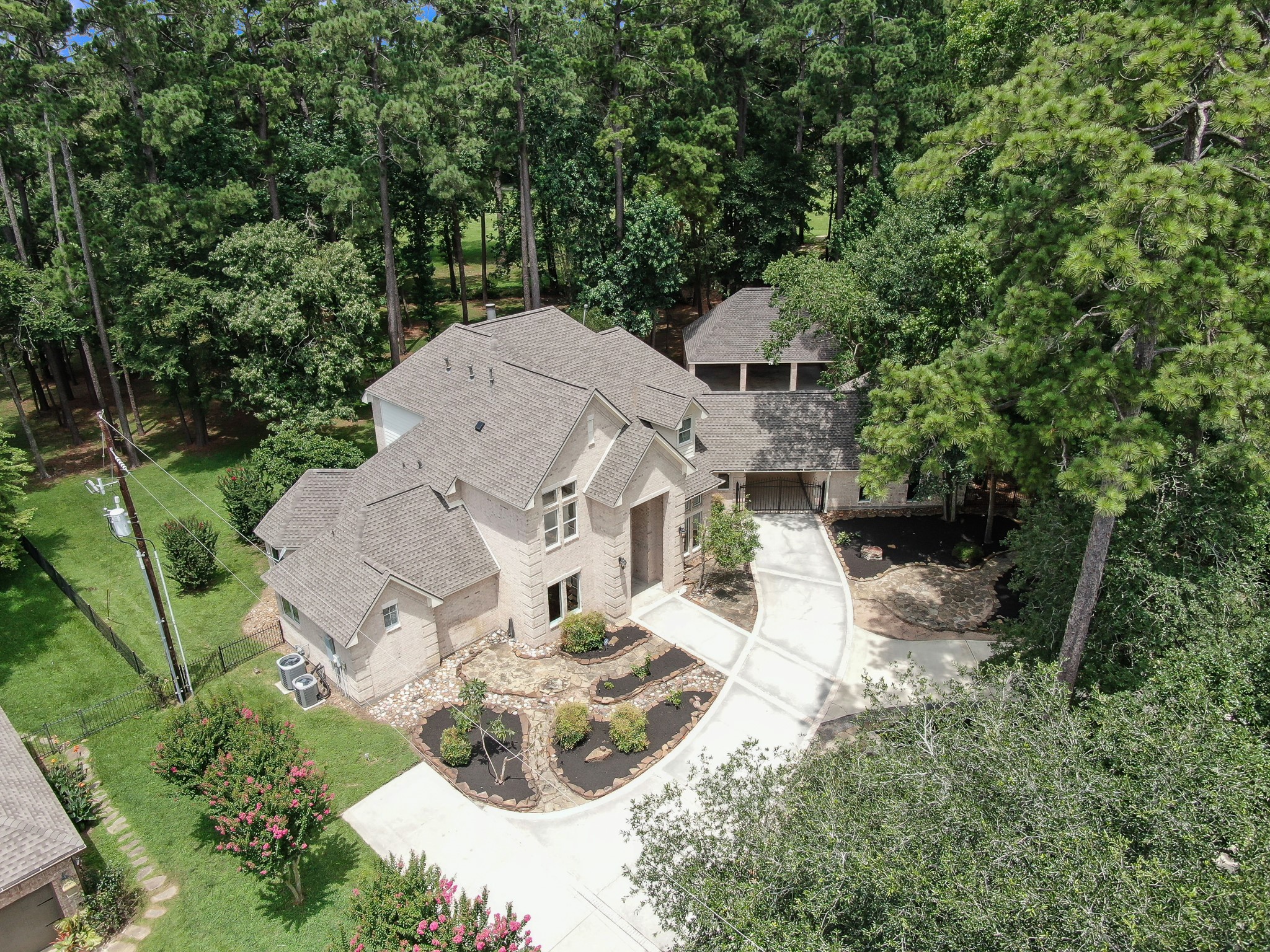 2205 Longmire Road Conroe, TX 77304 - Photo 41 of 49 Aerial view of this gorgeous home nestled among tall trees, offering privacy and a natural setting. The property features a long driveway sitting way back off the road with ample parking and a well-maintained landscaped garden.