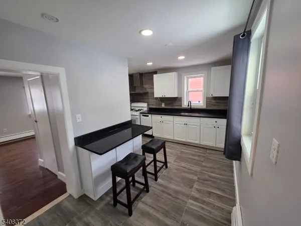 a kitchen with granite countertop a sink a stove a refrigerator and cabinets