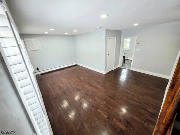 a view of an empty room with wooden floor and stairs