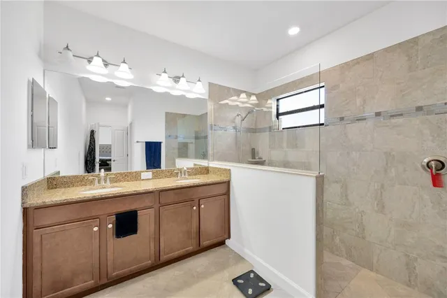 a spacious bathroom with a granite countertop sink a mirror and a shower