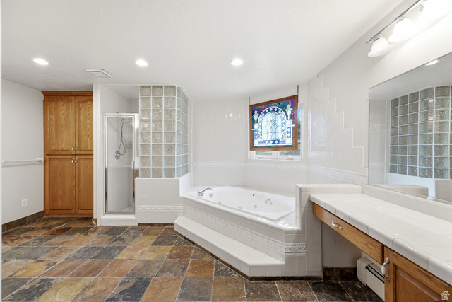 3535 Homestead Road Park City, UT 84098 - Photo 39 of 81 Spacious bathroom featuring a multi-toned slate tile floor, a built-in jetted tub, a glass-block shower enclosure, a stained-glass window, and a wood-finish vanity with a tile countertop