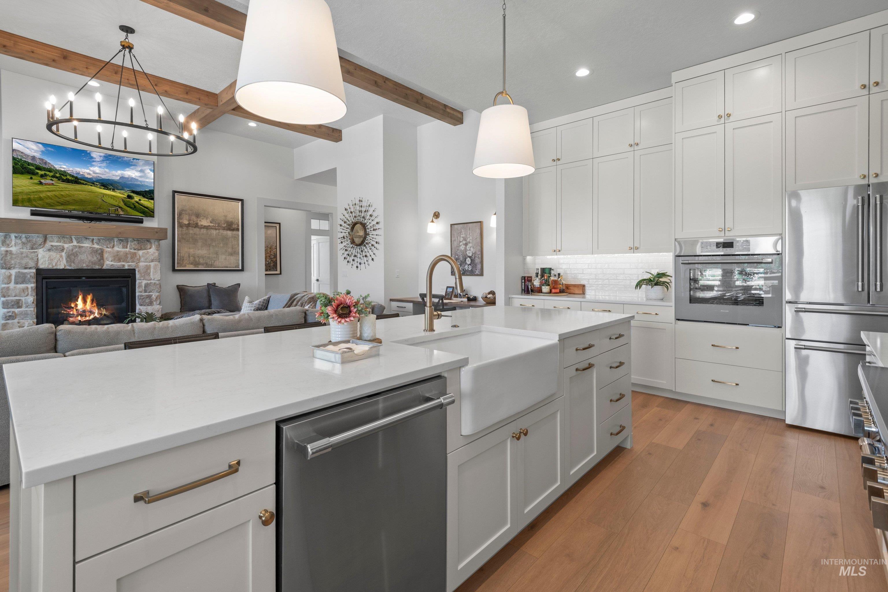 24990 Belgian Way Middleton, ID 83644 - Photo 12 of 50 Spacious kitchen featuring a large central island with a farmhouse sink, stainless steel dishwasher, and light-toned countertops