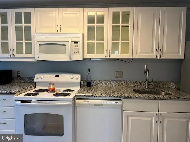 a kitchen with granite countertop a stove a sink and a microwave