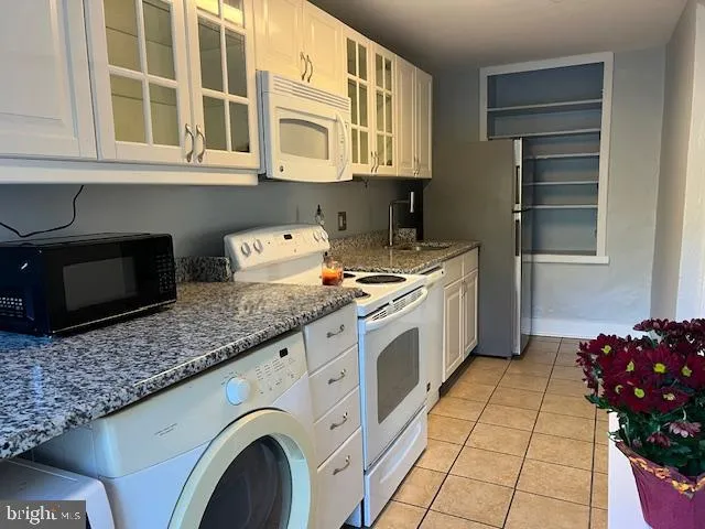 a kitchen with granite countertop a stove a sink and a microwave