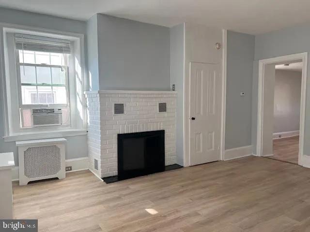a view of empty room with wooden floor and fireplace