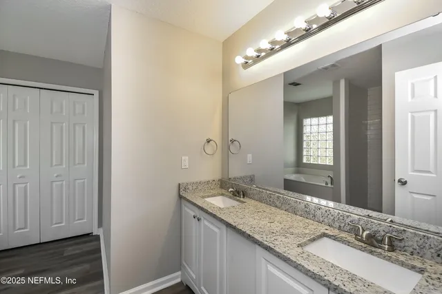 a bathroom with a granite countertop double vanity and a mirror