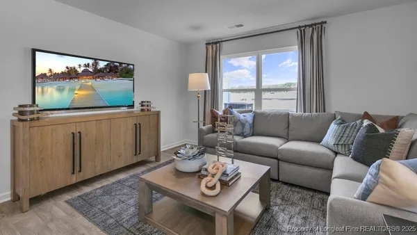 a living room with furniture potted plant and kitchen view