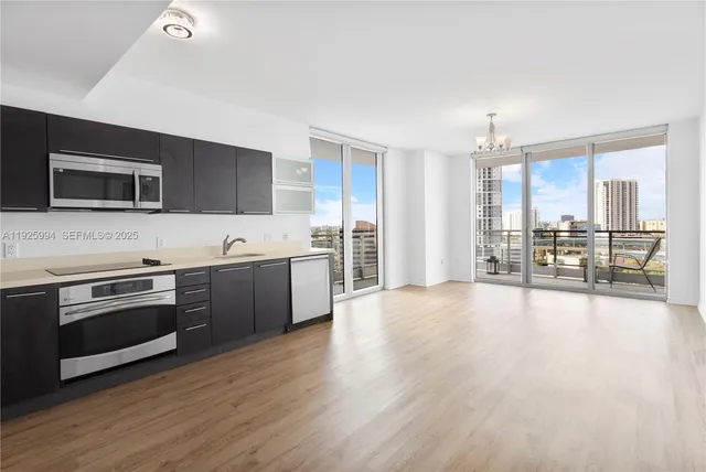 a large kitchen with stainless steel appliances wooden floor and a counter top space