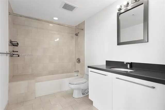a bathroom with a granite countertop sink a toilet and shower