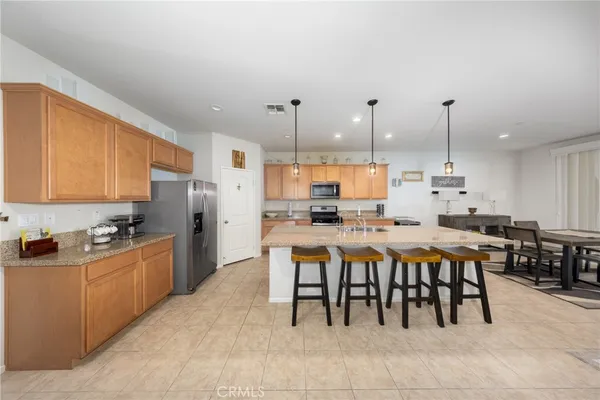 a kitchen with kitchen island granite countertop a table chairs sink and cabinets