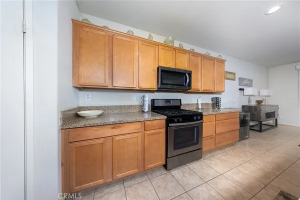 a kitchen with stainless steel appliances granite countertop a stove top oven a sink dishwasher and white cabinets with wooden floor