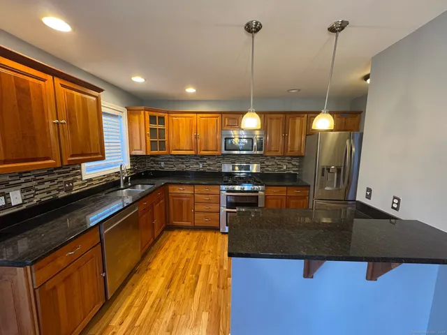 a kitchen with stainless steel appliances granite countertop a sink a stove and a wooden floors