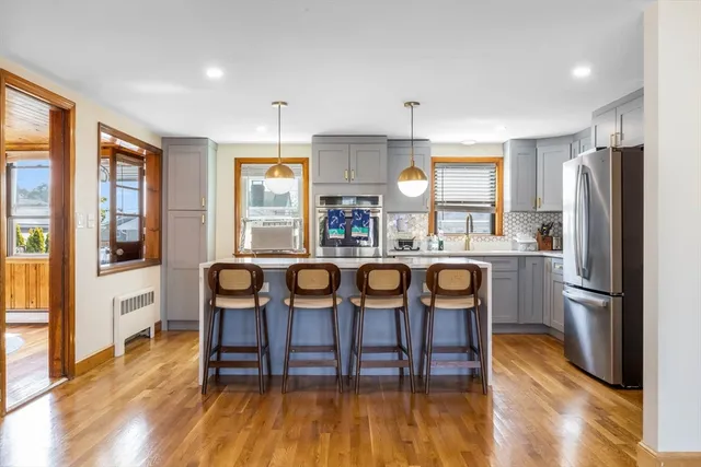 a kitchen with stainless steel appliances granite countertop a dining table chairs refrigerator and sink