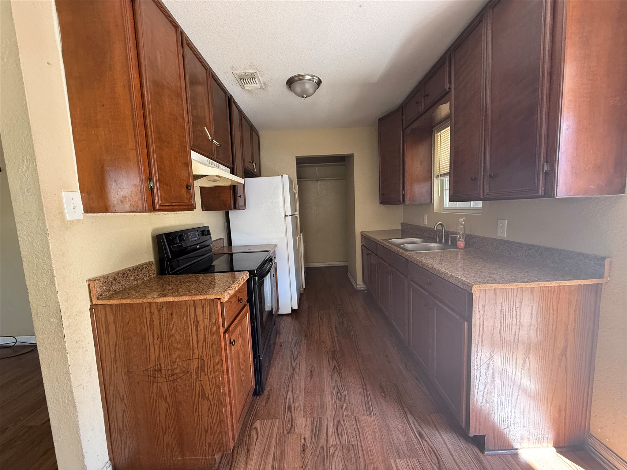 15501 Connie Street Austin, TX 78728 - Photo 7 of 26 Kitchen featuring black electric range, dark wood-type flooring, a textured wall, dark countertops, and freestanding refrigerator