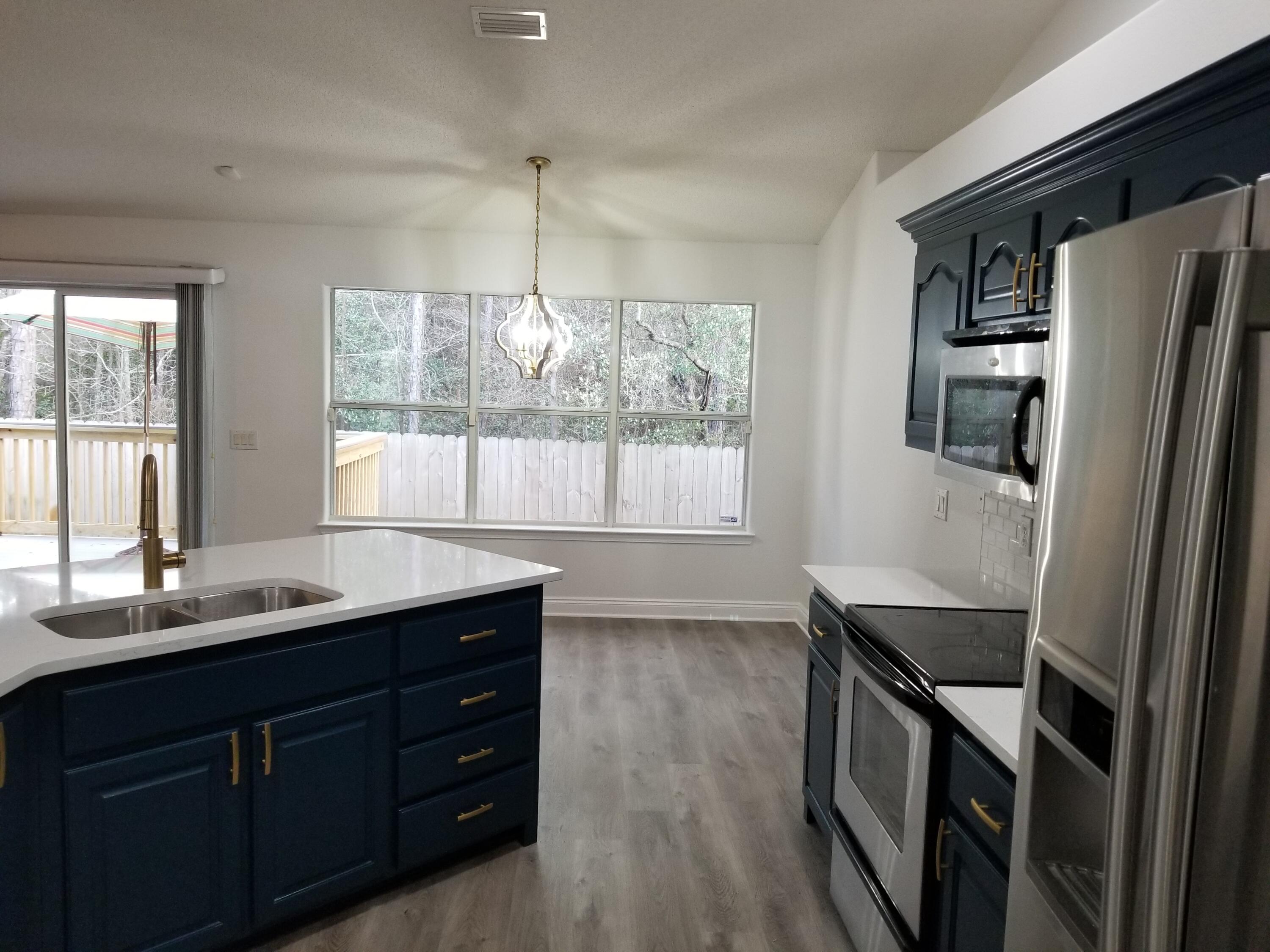6673 Redfield Street Navarre, FL 32566 - Photo 17 of 32 a kitchen with granite countertop a refrigerator and a sink