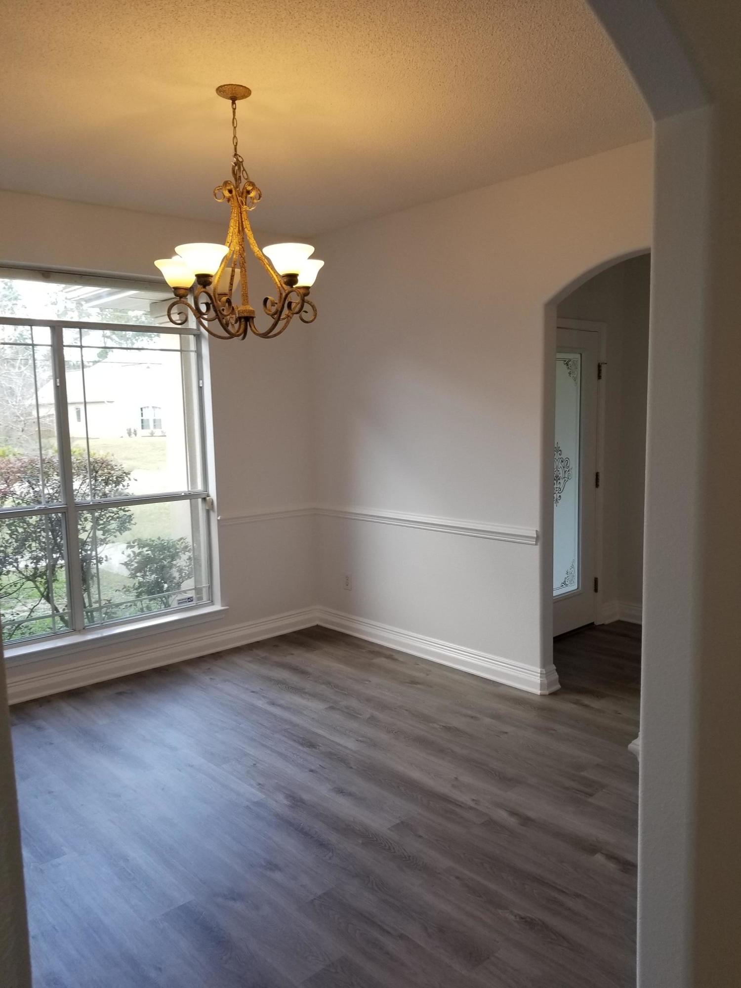 6673 Redfield Street Navarre, FL 32566 - Photo 5 of 32 an empty room with wooden floor chandelier and windows