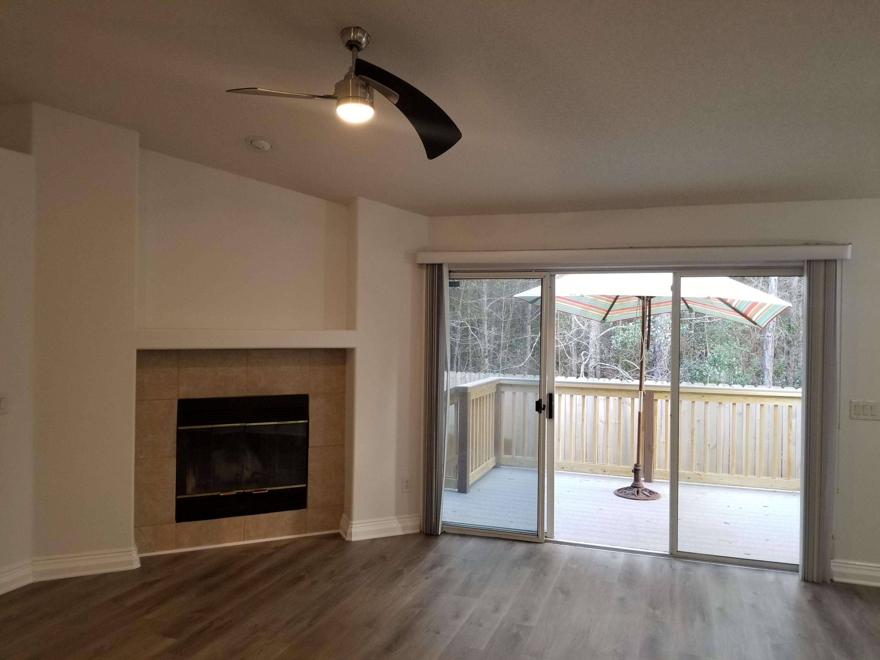 6673 Redfield Street Navarre, FL 32566 - Photo 6 of 32 an empty room with wooden floor fireplace and windows