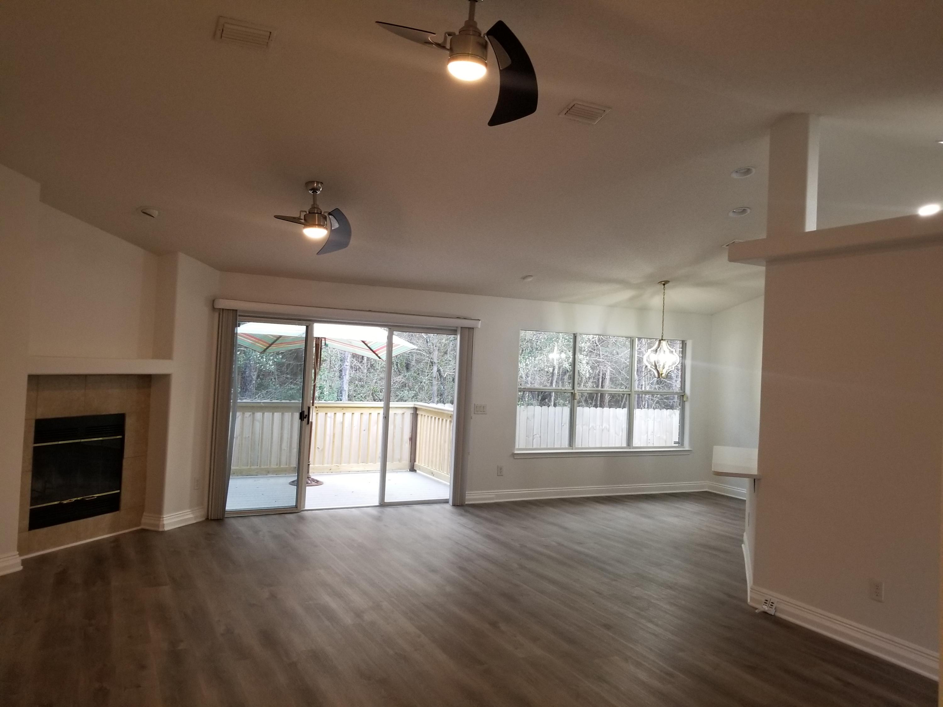 6673 Redfield Street Navarre, FL 32566 - Photo 7 of 32 an empty room with wooden floor and fireplace