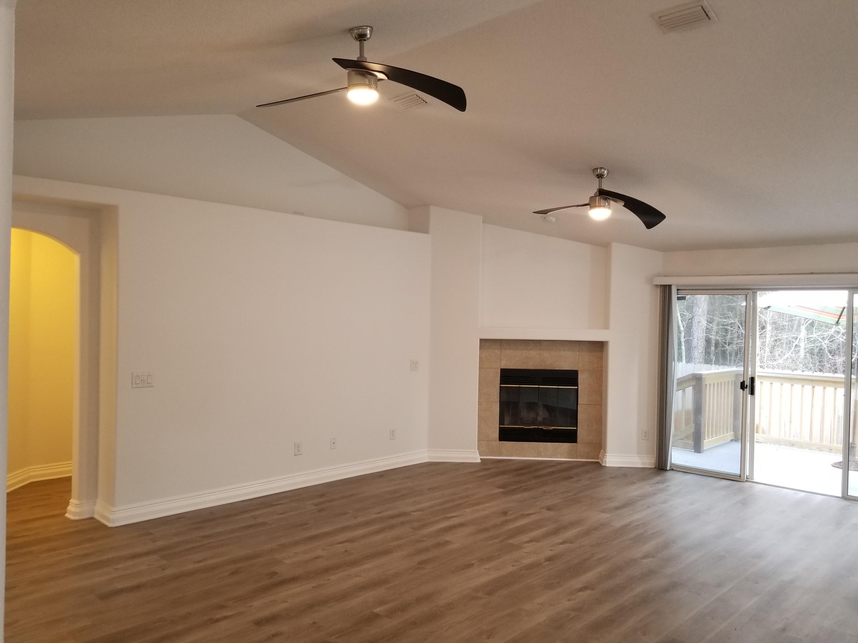 6673 Redfield Street Navarre, FL 32566 - Photo 8 of 32 an empty room with wooden floor fireplace and windows