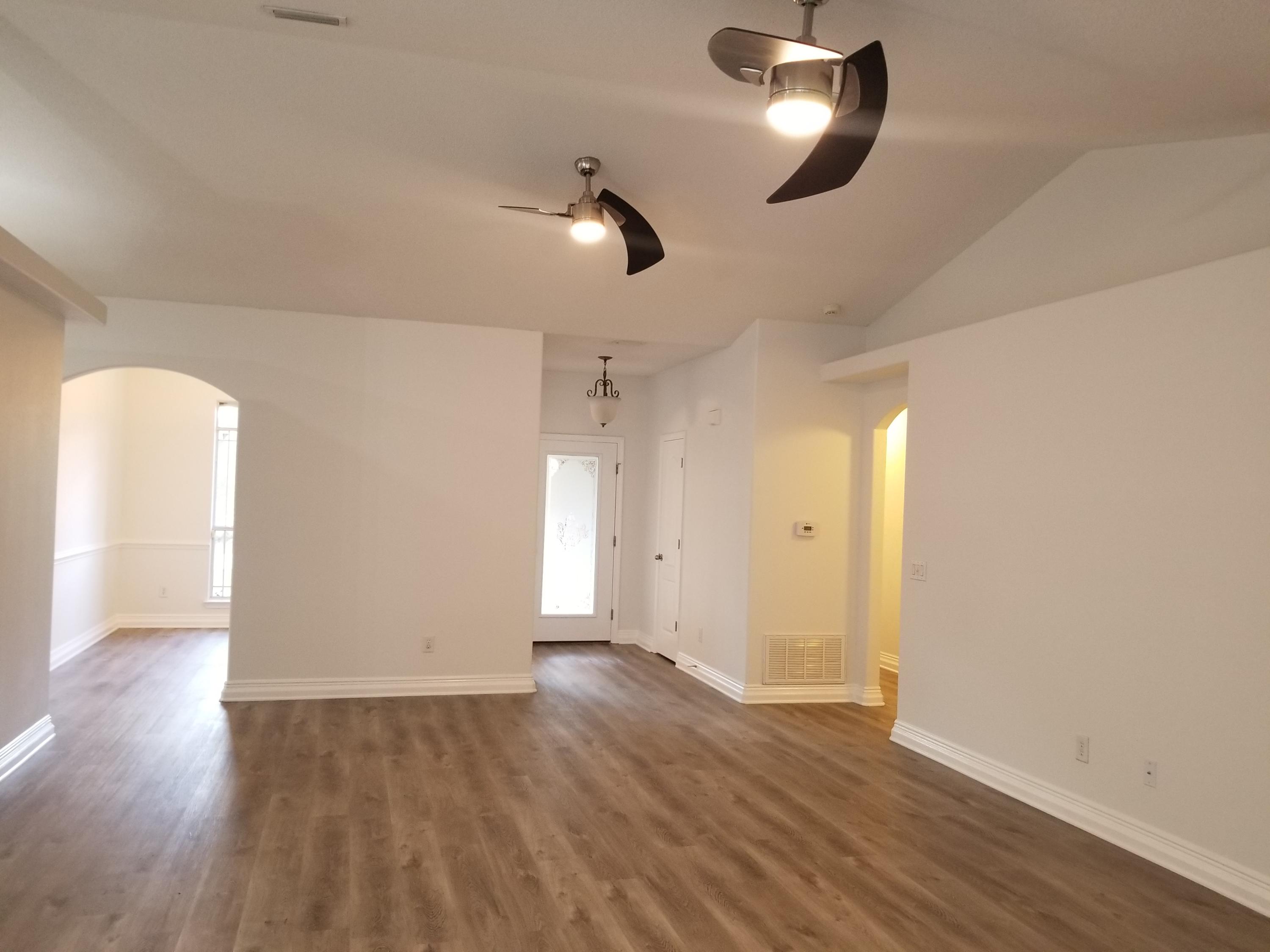 6673 Redfield Street Navarre, FL 32566 - Photo 9 of 32 an empty room with wooden floor and windows