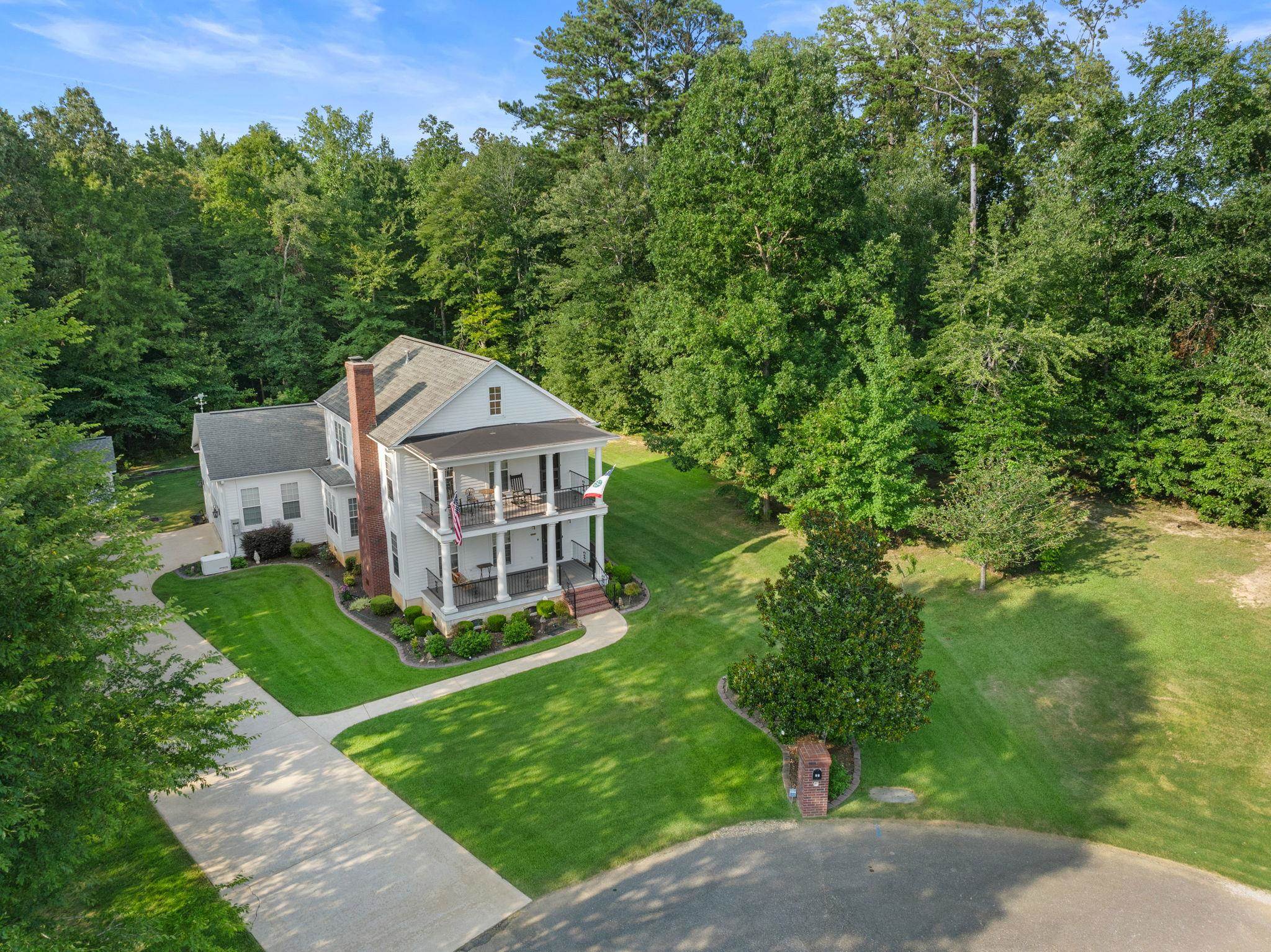 a view of a house with a yard and large trees