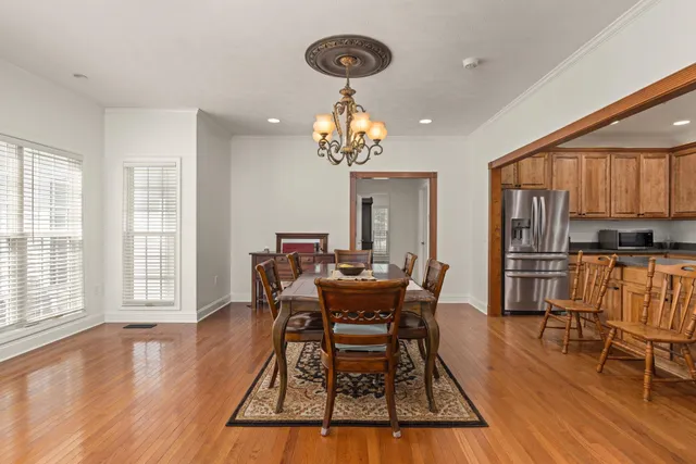 a dining room with wooden floor a chandelier a glass table and chairs