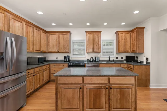 a kitchen with stainless steel appliances granite countertop a refrigerator a sink dishwasher a stove and white countertops with wooden floor