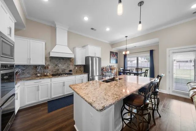 a kitchen with granite countertop kitchen island granite countertop a table chairs sink and cabinets