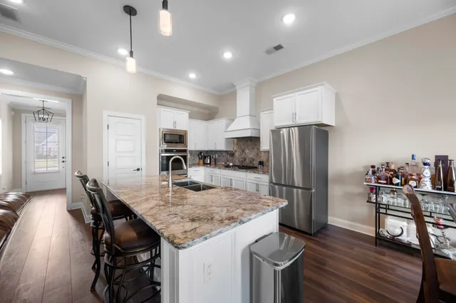 a kitchen with granite countertop kitchen island wooden floor center island and stainless steel appliances