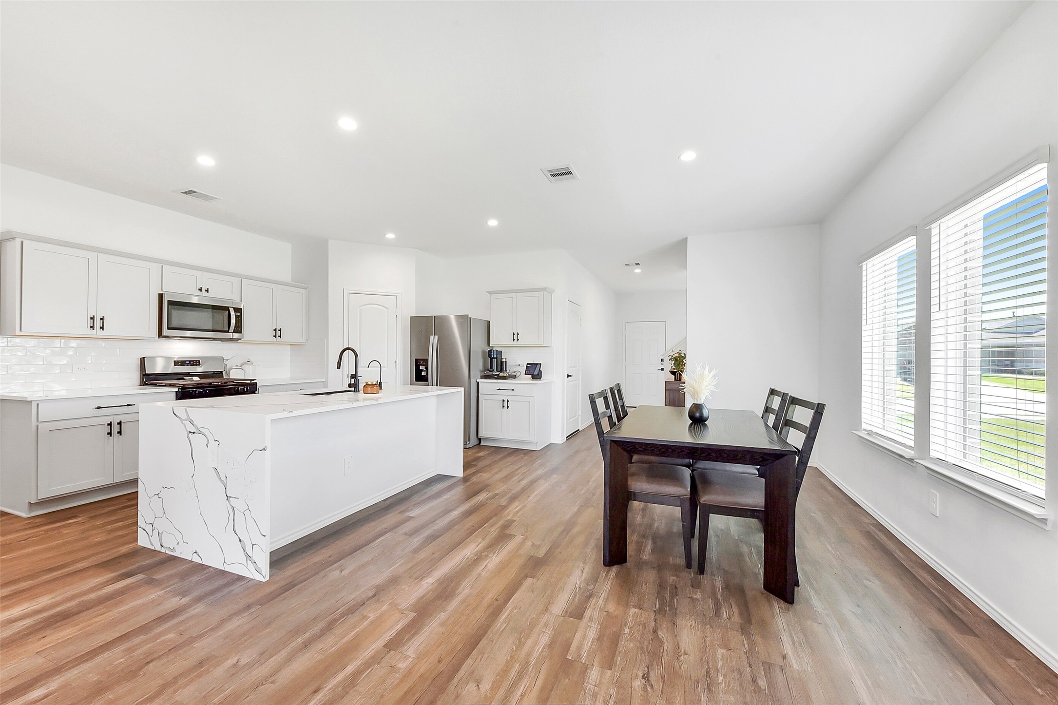24222 Sandstone Valley Ln Spring Spring, TX 77373 - Photo 12 of 32 a kitchen with white cabinets wooden floor and stainless steel appliances