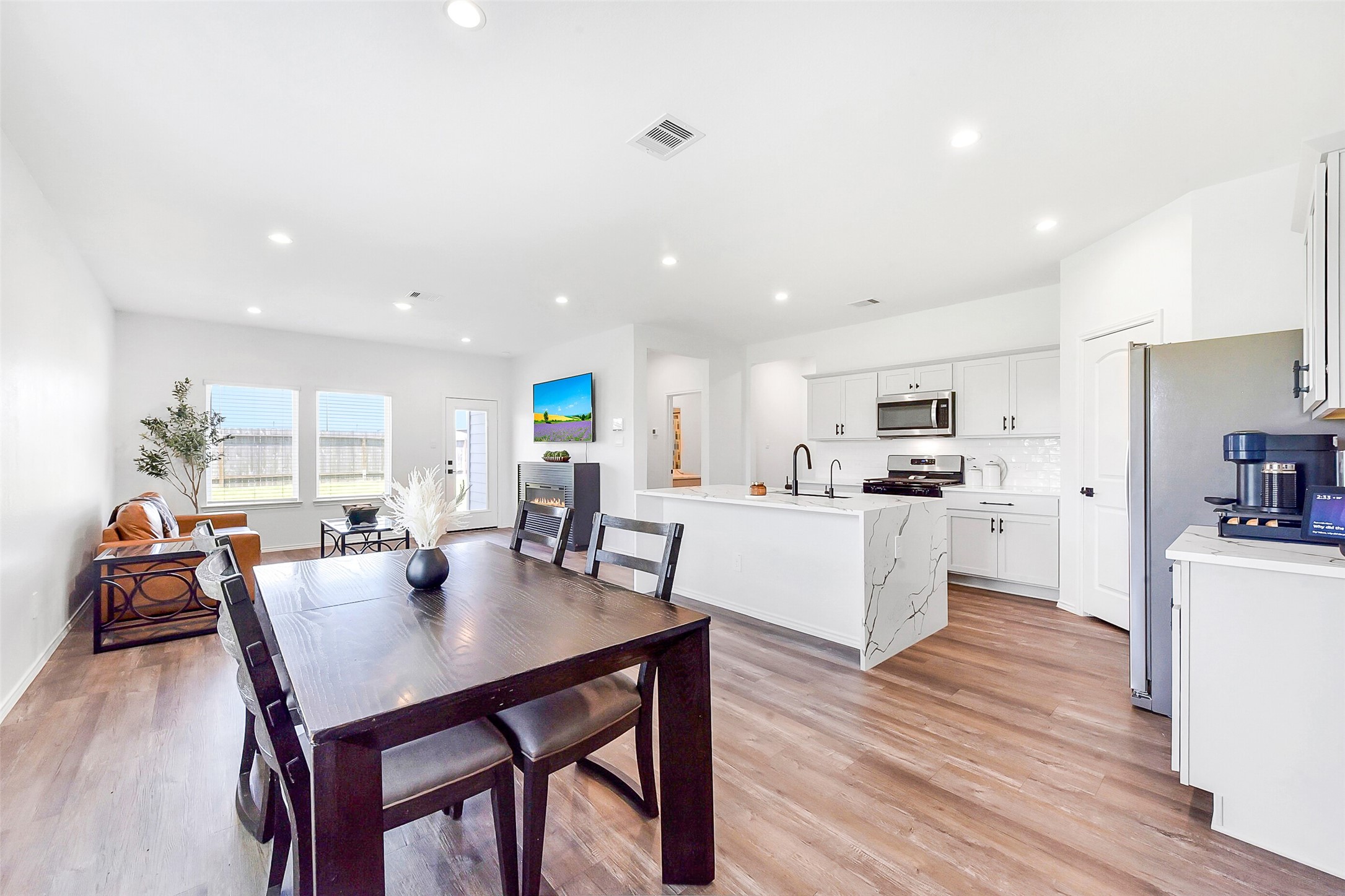 24222 Sandstone Valley Ln Spring Spring, TX 77373 - Photo 13 of 32 a kitchen with stainless steel appliances kitchen island granite countertop a table chairs and white cabinets