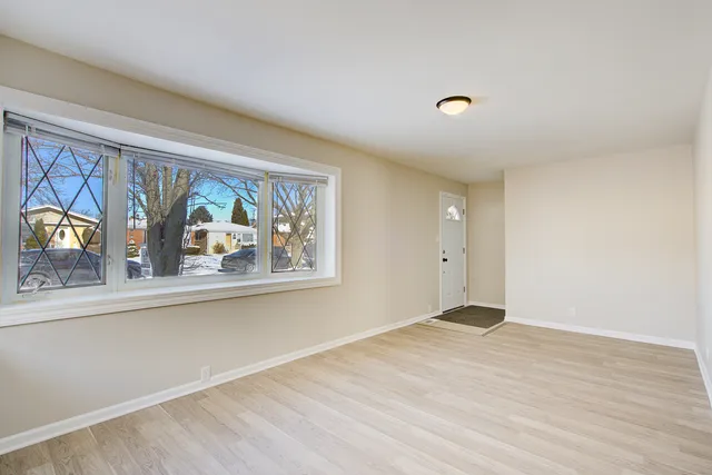 a view of an empty room with window and wooden floor