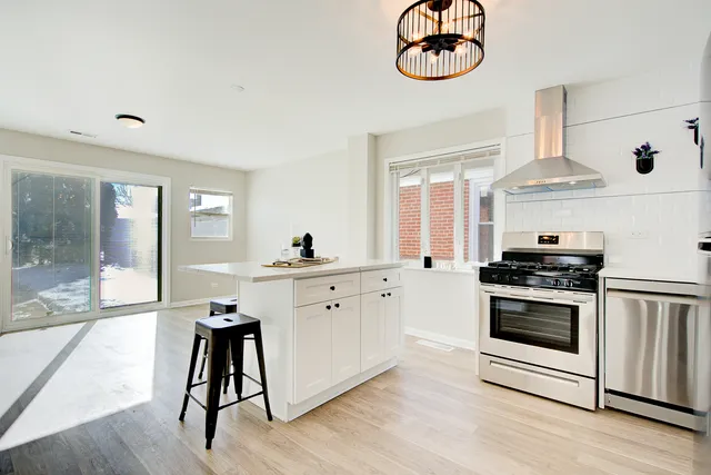 a kitchen with stainless steel appliances a stove a sink and a large window
