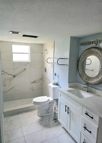 a bathroom with a granite countertop sink mirror vanity and toilet