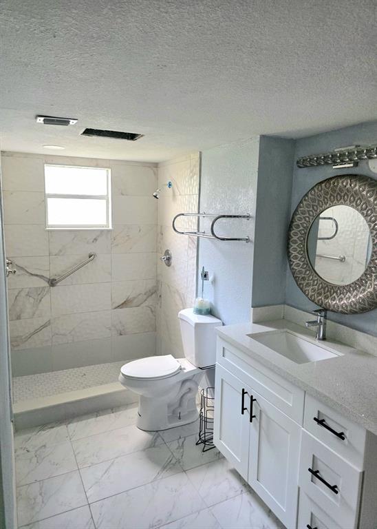 a bathroom with a granite countertop sink mirror vanity and toilet
