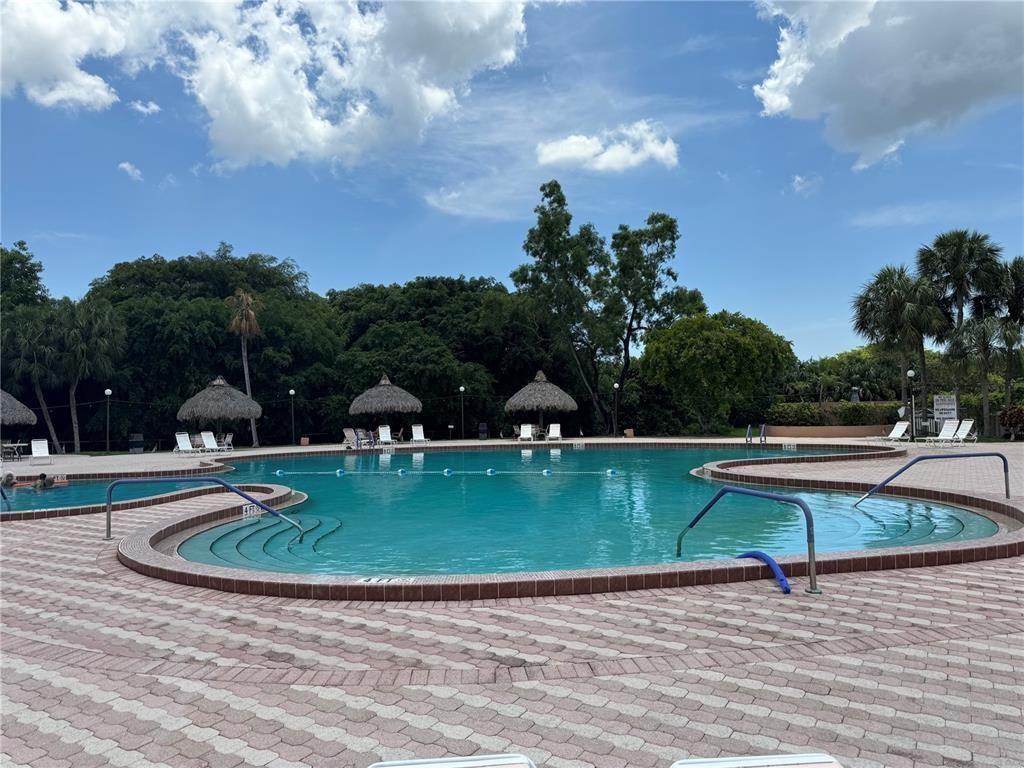 3130 Holiday Springs Boulevard, Unit 104 Margate, FL 33063 - Photo 7 of 7 a view of a swimming pool with a table and chairs under an umbrella