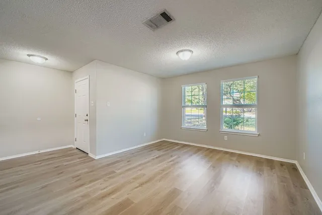 an empty room with wooden floor and windows