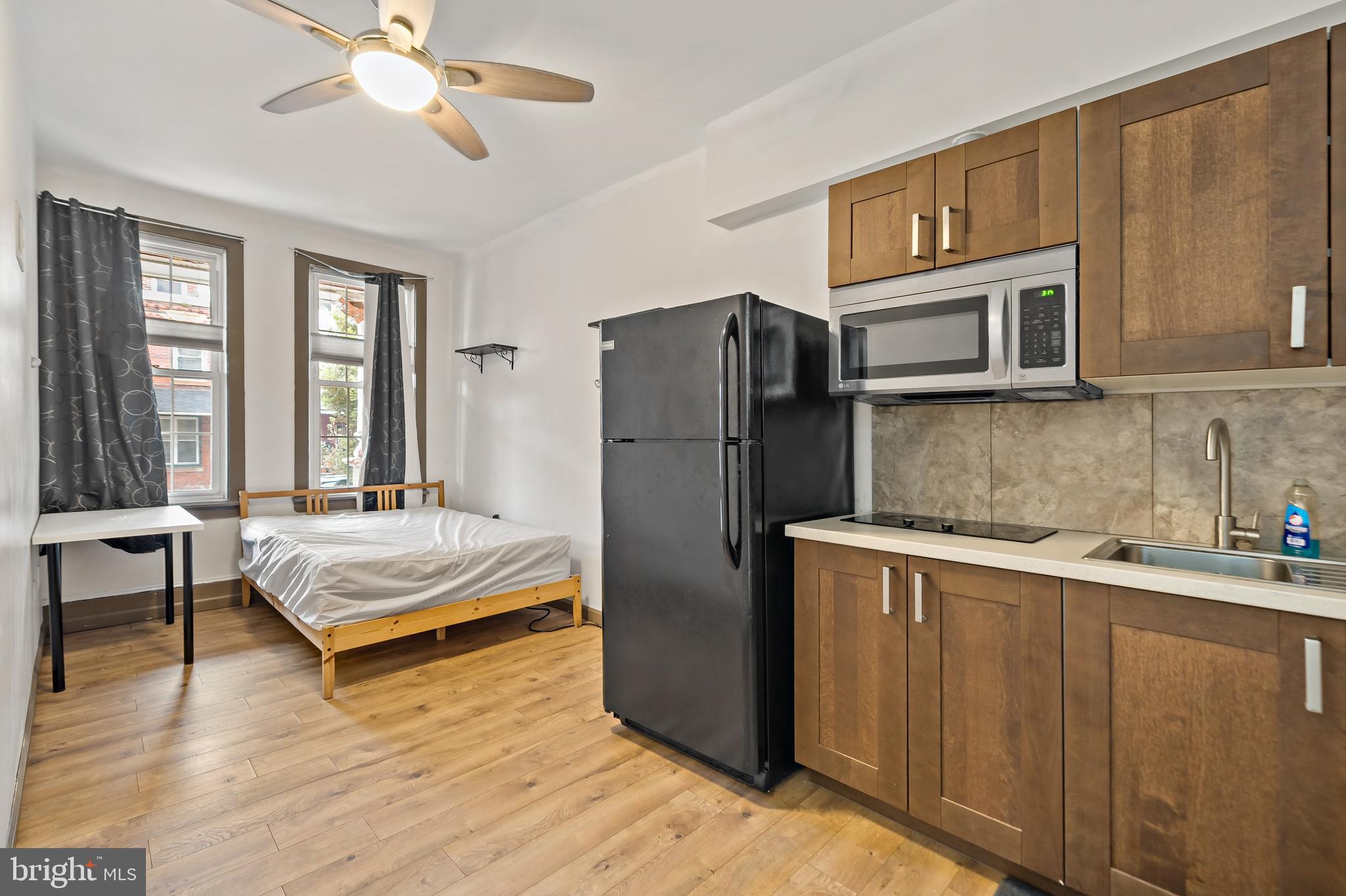 653 North 33rd Street Philadelphia, PA 19104 - Photo 5 of 28 a living room with stainless steel appliances granite countertop a refrigerator a stove a sink dishwasher and microwave with wooden floor