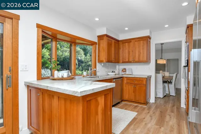 a kitchen with stainless steel appliances granite countertop a refrigerator a sink dishwasher and wooden cabinets with wooden floor