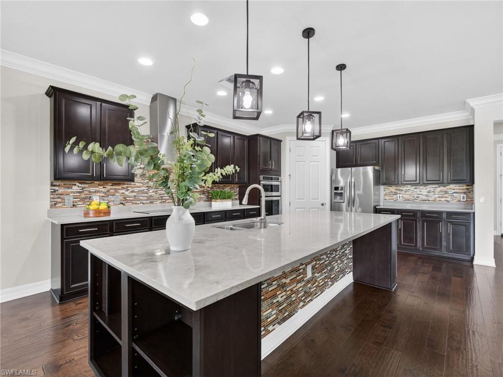 6124 Victory Drive Ave Maria, FL 34142 - Photo 6 of 50 a large kitchen with stainless steel appliances kitchen island granite countertop a table chairs and a wooden floor