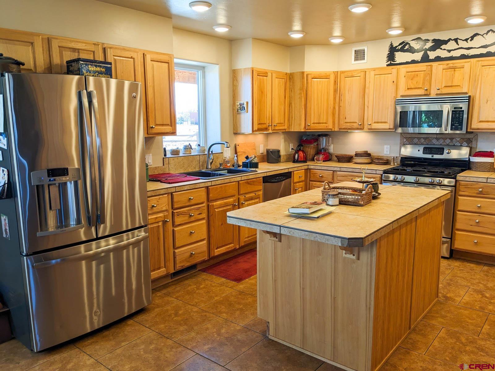 1244 Ash Mesa Road Delta, CO 81416 - Photo 7 of 35 a kitchen with stainless steel appliances granite countertop a refrigerator a sink and a stove