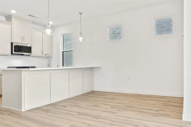 a large white kitchen with kitchen island a sink stainless steel appliances and cabinets