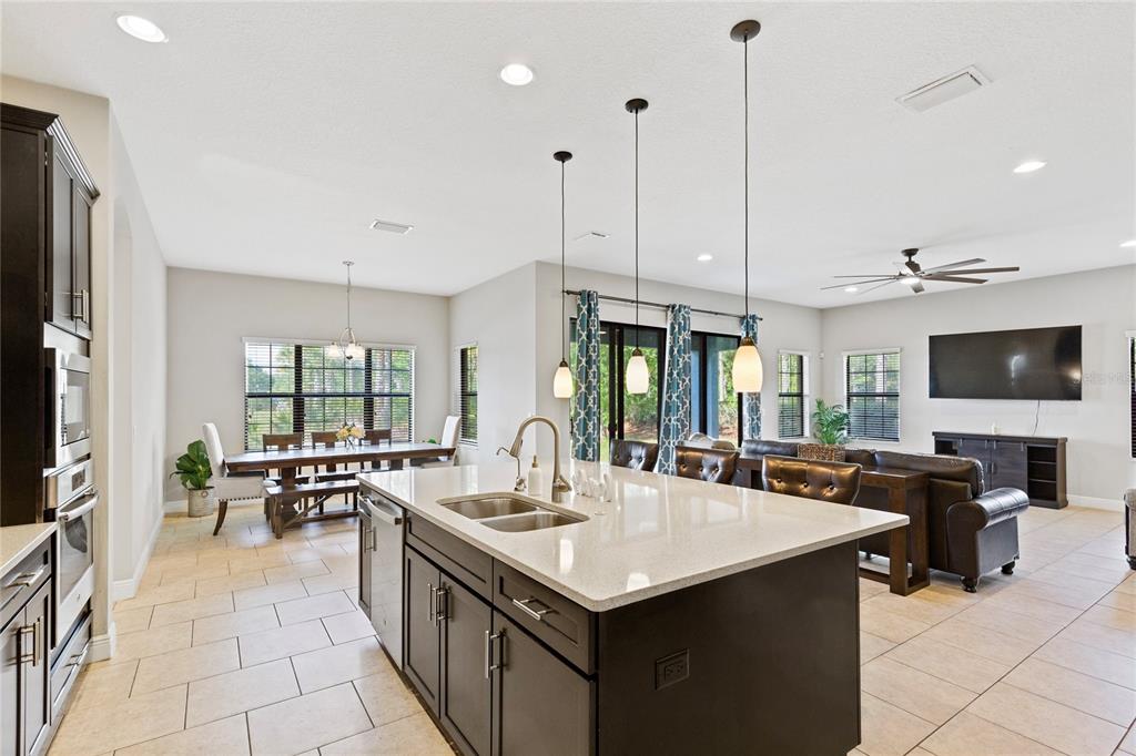 31976 Watoga Loop Wesley Chapel, FL 33543 - Photo 12 of 47 a large kitchen with kitchen island a sink a counter top space and living room view