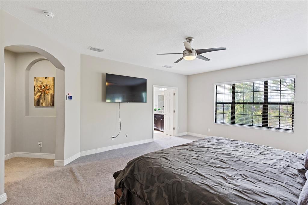 31976 Watoga Loop Wesley Chapel, FL 33543 - Photo 21 of 47 a bedroom with a large bed and a flat tv screen on dresser