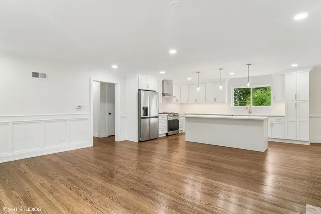 a view of kitchen with kitchen island wooden floors appliances and cabinets